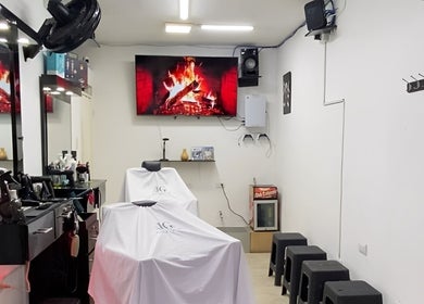 Interior moderno de Jg Barbería en Cali, Valle Del Cauca, CO con sillas tapadas y pantalla decorativa.
