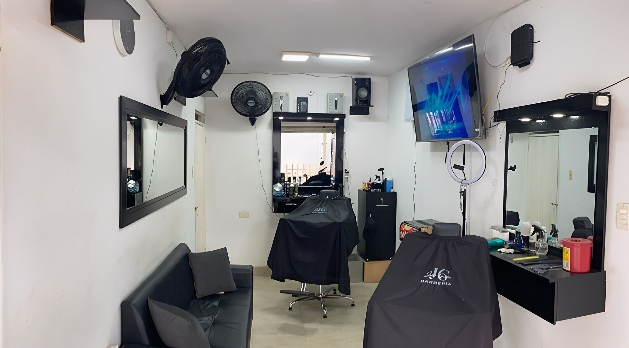 Interior moderno de Jg Barbería en Cali, Valle Del Cauca, CO con sillas y espejos elegantes.