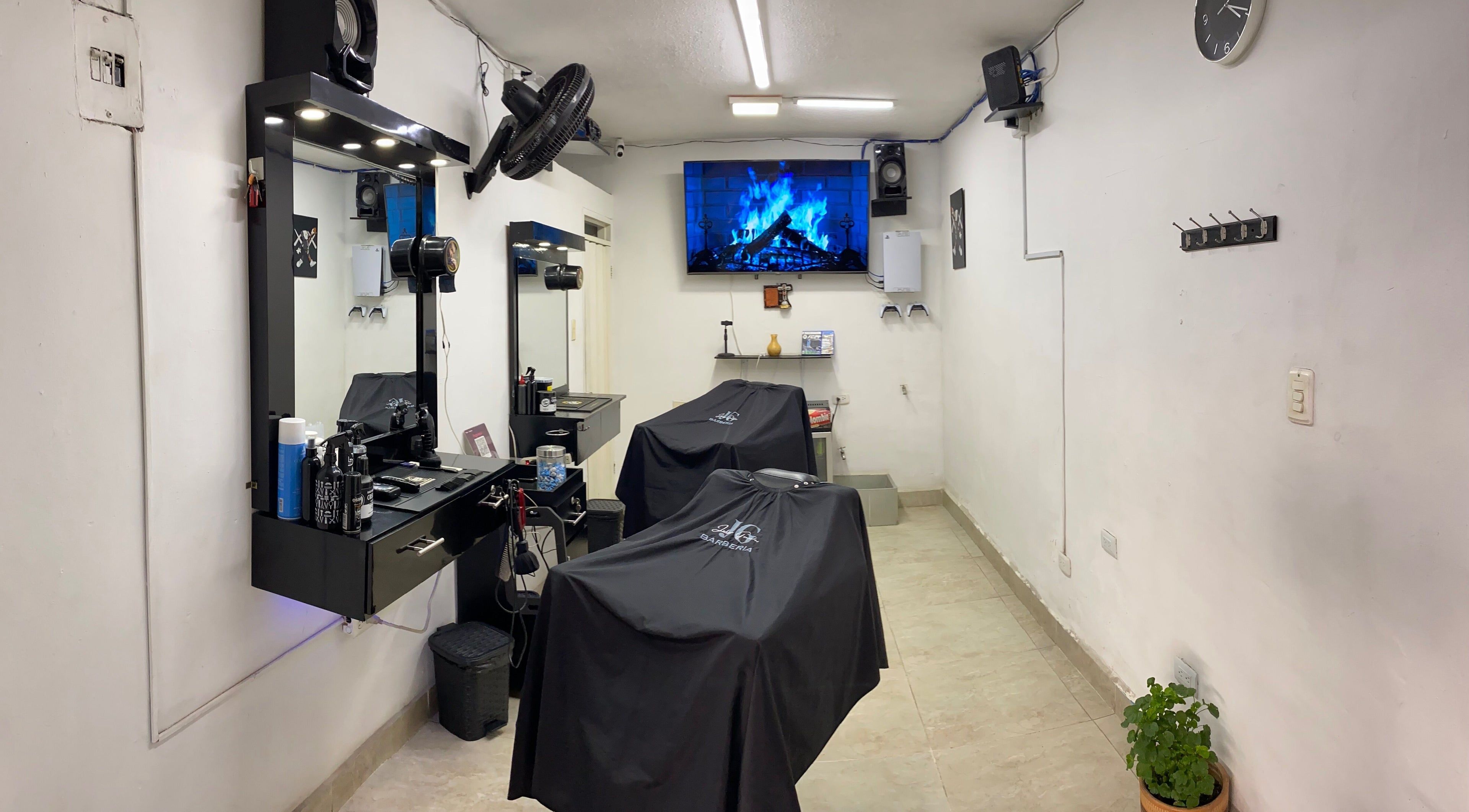 Interior moderno de Jg Barbería en Cali, Valle Del Cauca, CO, con estaciones de trabajo y pantalla.