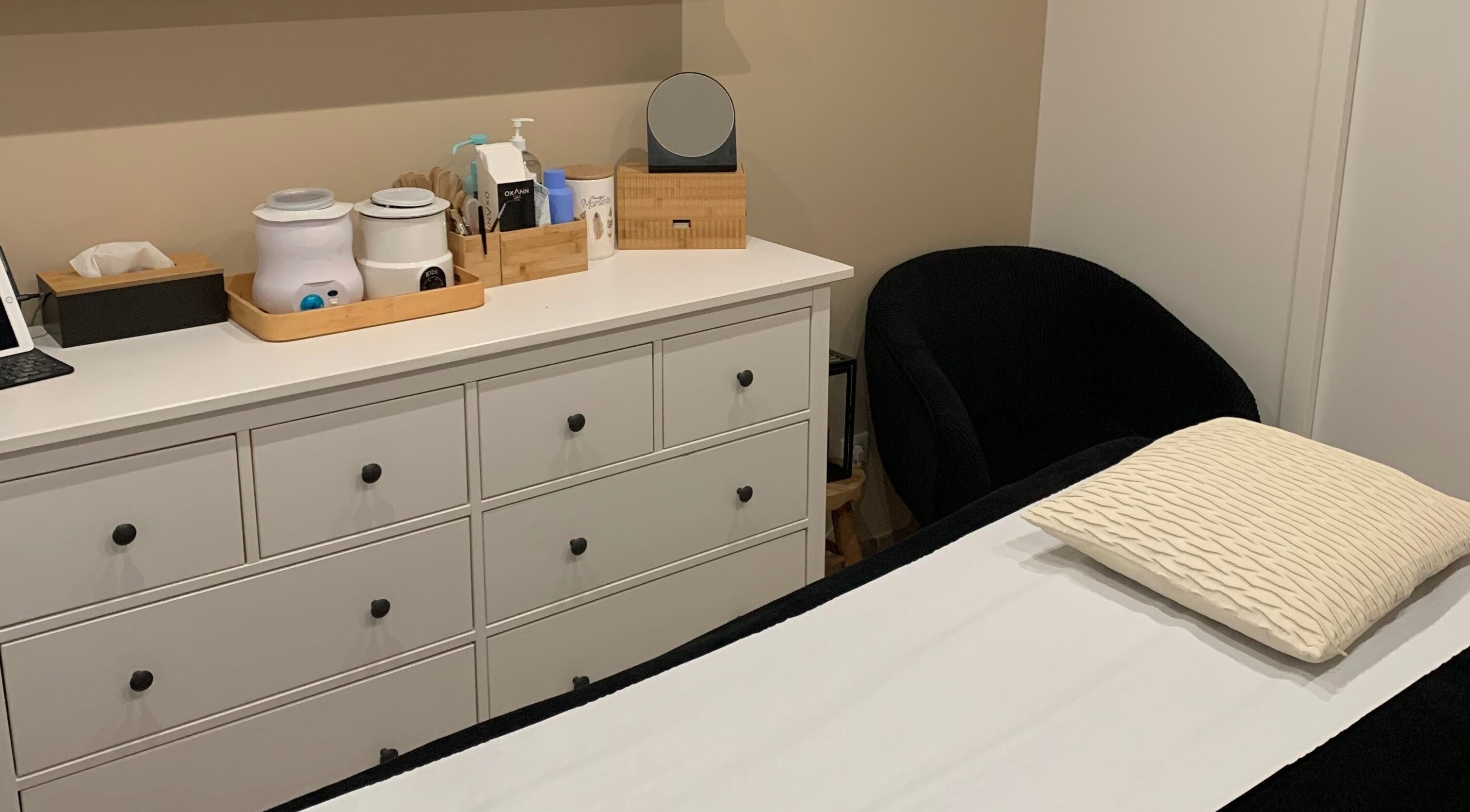 Salle de soin sereine à Studio Beauté by Julie, Théville, Normandie, FR avec table et commode bien rangée.