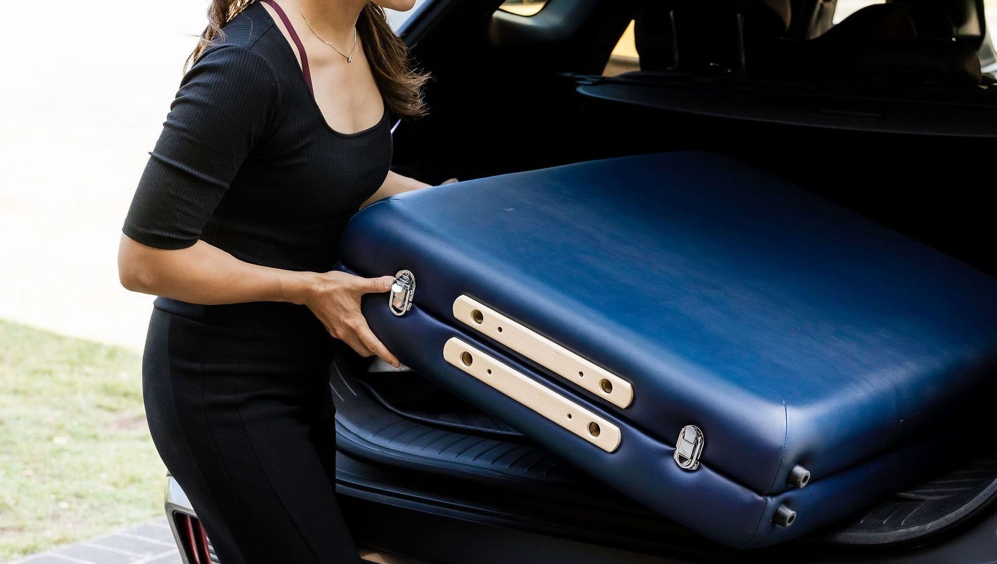 Woman removing massage table from car at Eden By Eva, Brisbane, Queensland, AU.