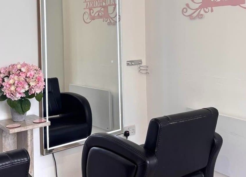 Elegant interior of Euphoria Hairdressing in Bath, England, GB with plush chair and floral decor.