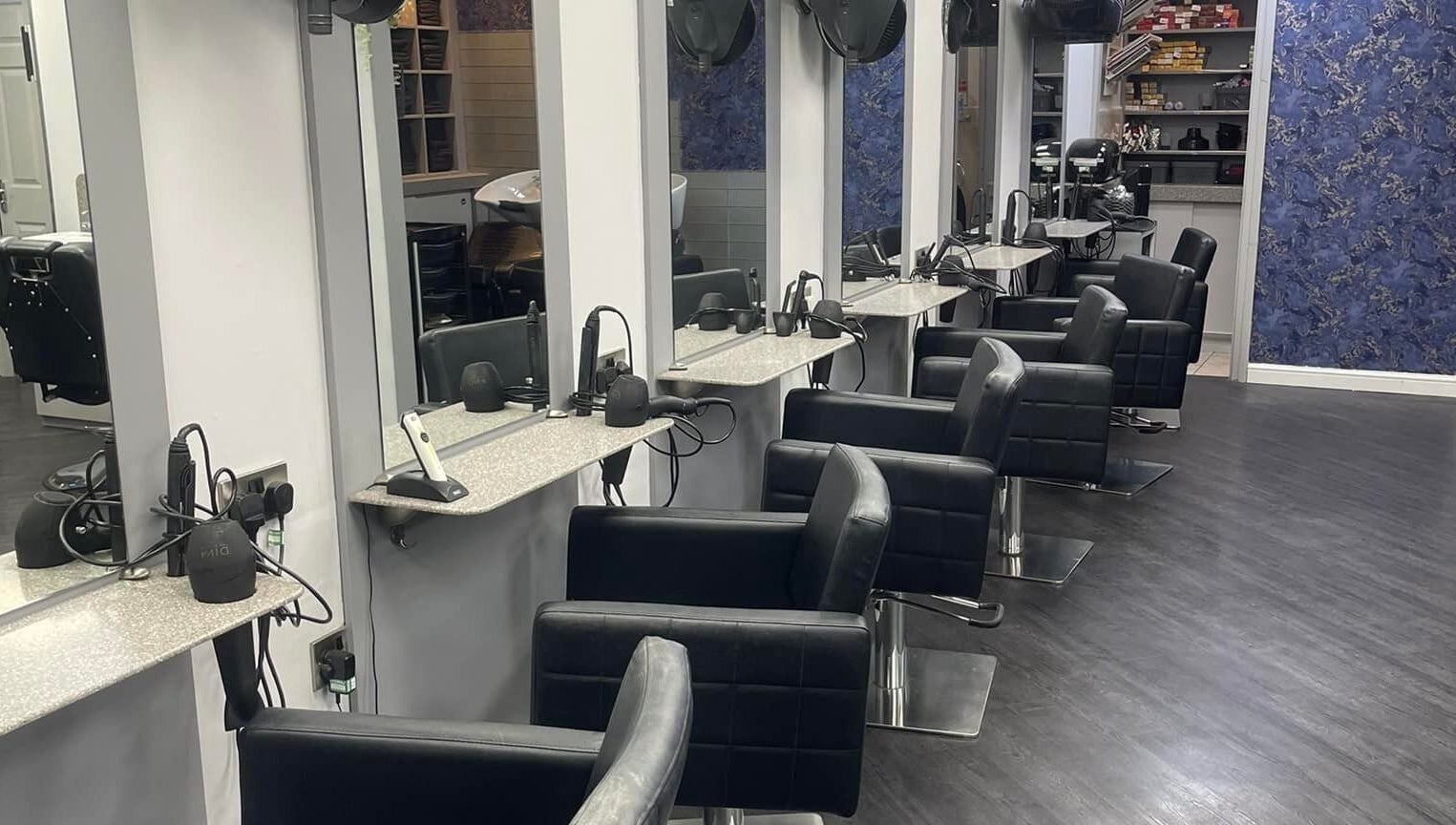 Modern salon interior at Hairtek, Yarm, England, GB with stylish black chairs and sleek mirrors.