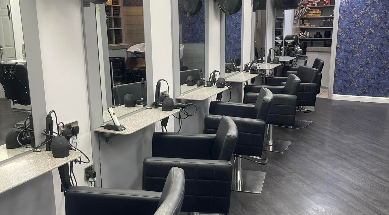 Modern salon interior at Hairtek, Yarm, England, GB with stylish black chairs and sleek mirrors.