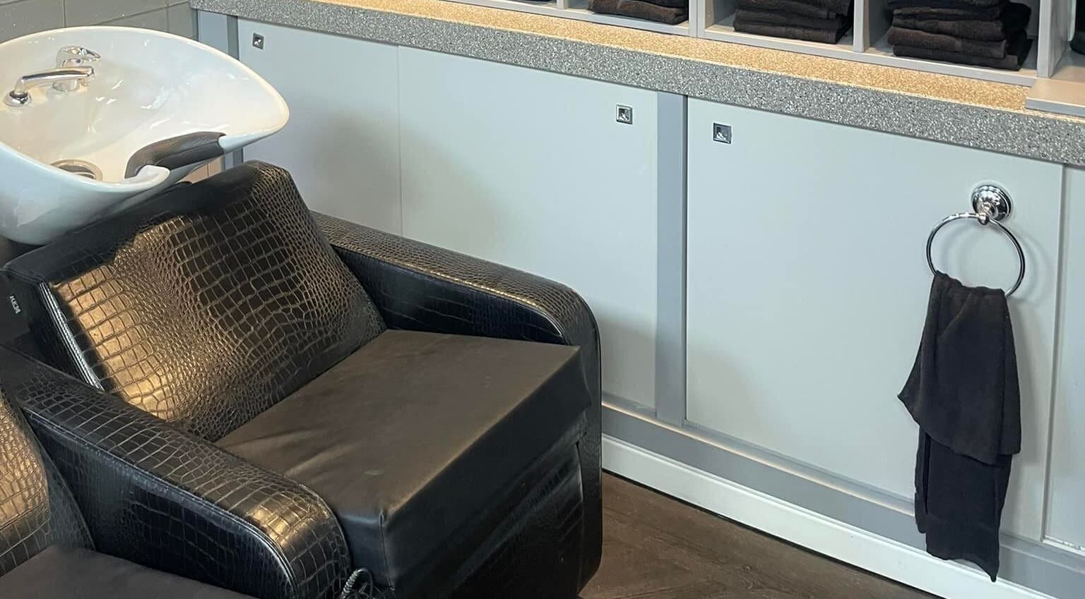 Luxury salon wash station at Hairtek, Yarm, England, GB, featuring sleek black leather seating.