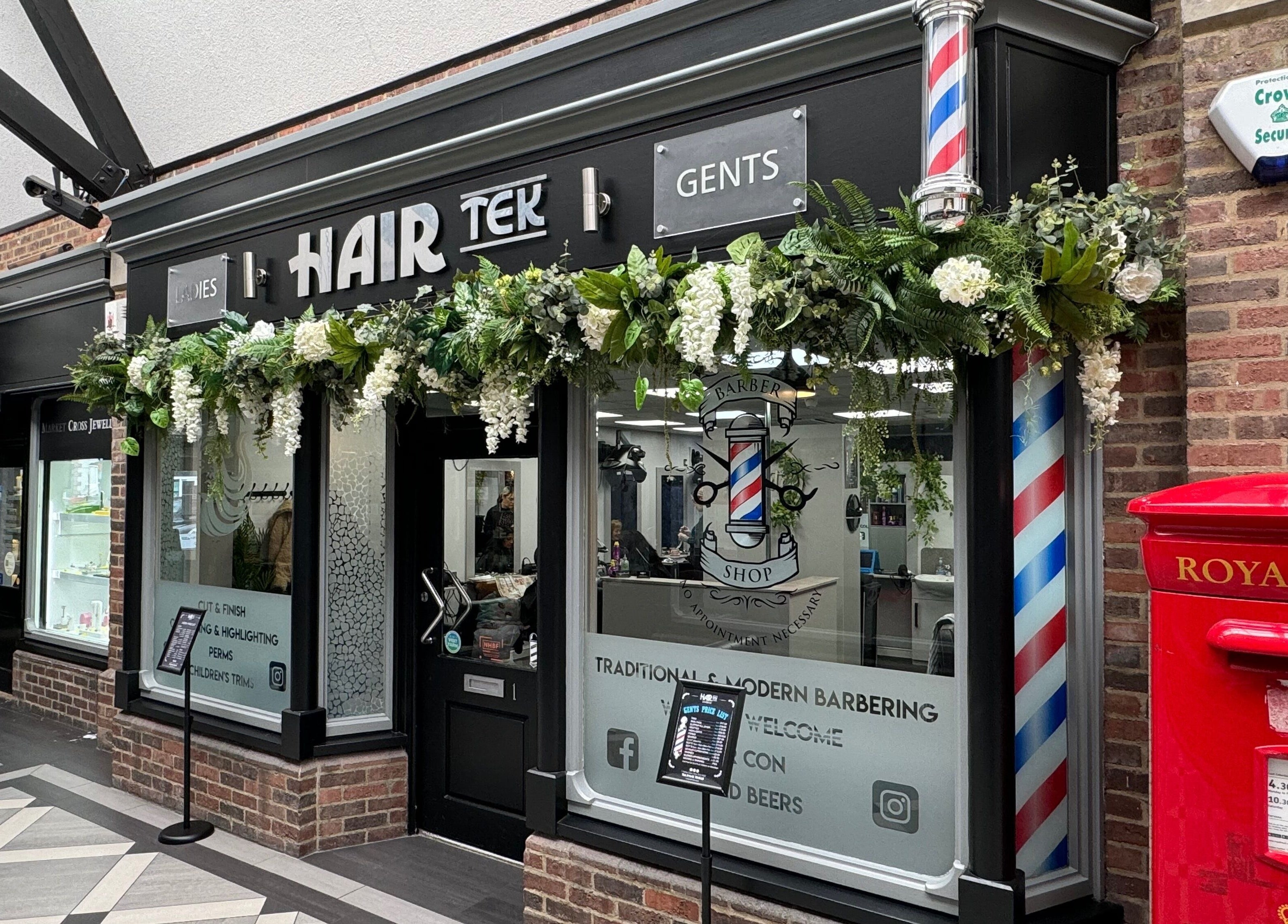 Hairtek salon facade in Yarm, England with elegant greenery and barber poles.