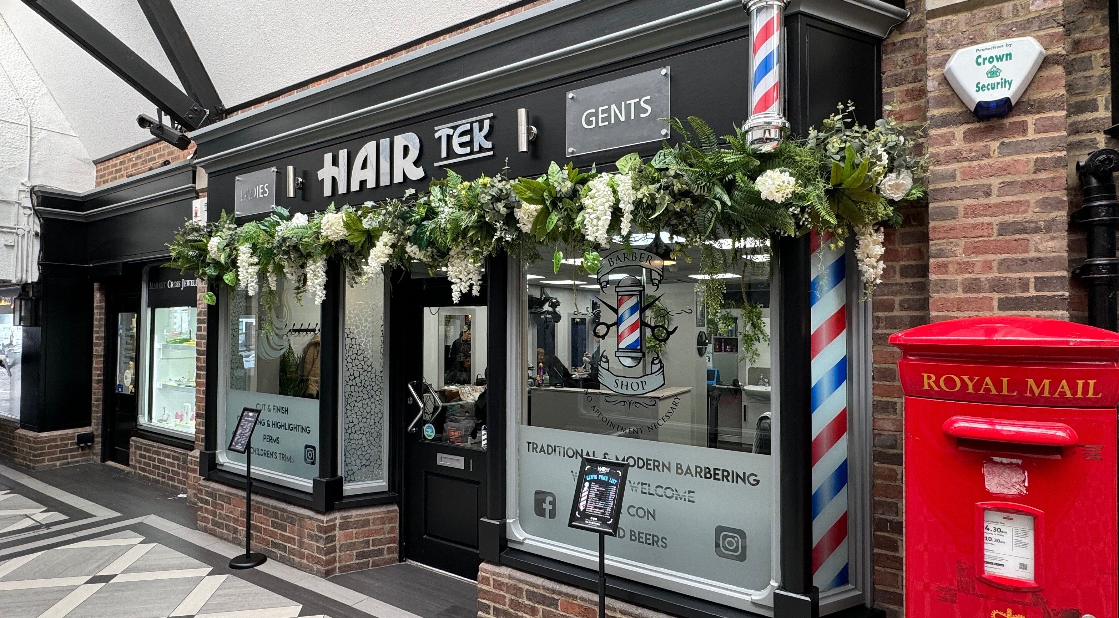 Hairtek salon facade in Yarm, England with elegant greenery and barber poles.