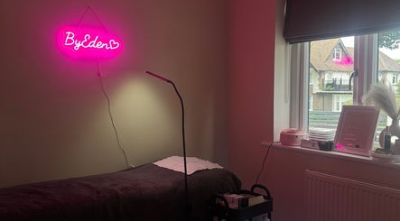 Elegant beauty treatment room at Lashes by Eden, Brighton And Hove, England, GB featuring neon sign and treatment bed.