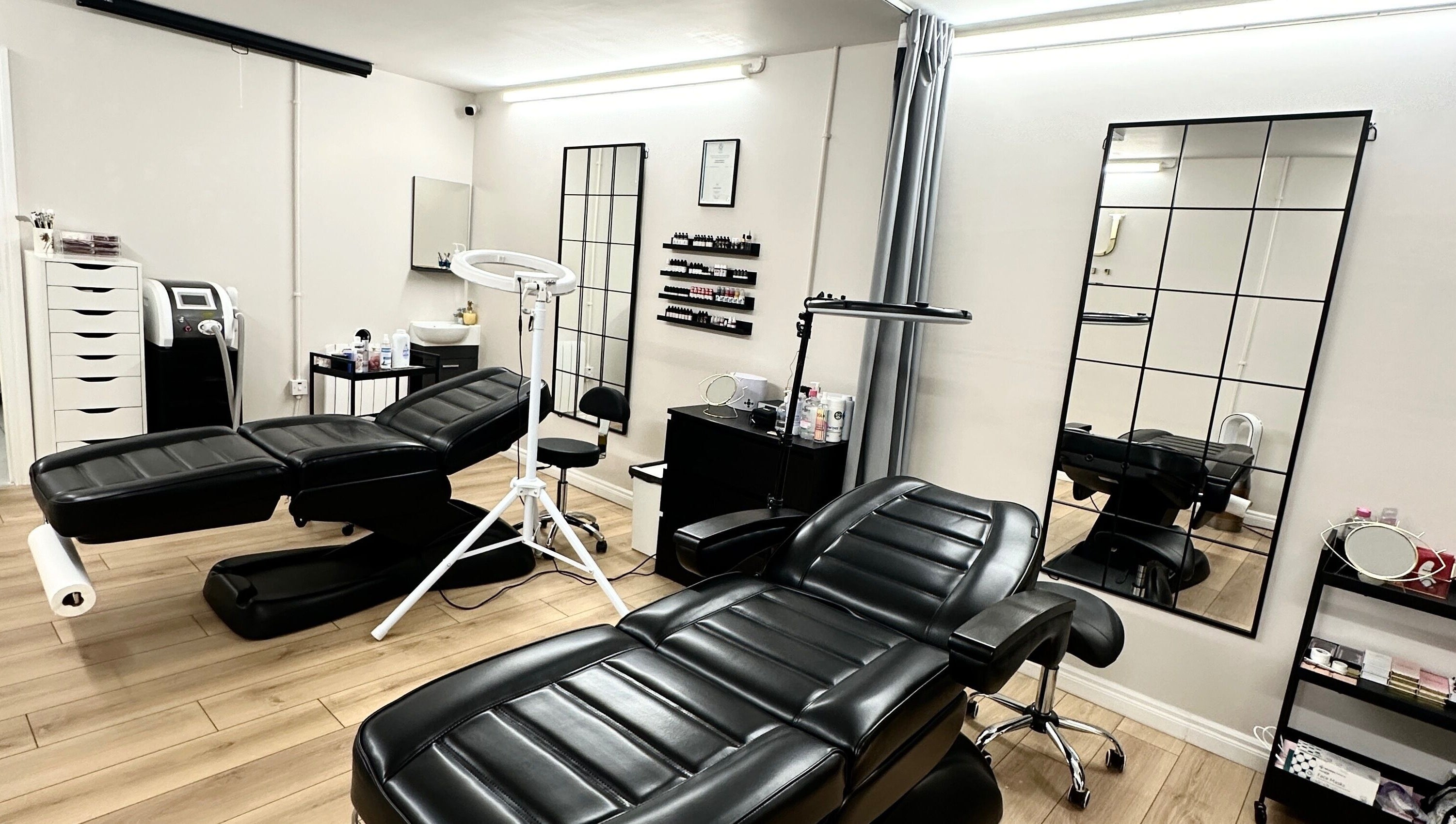 Modern treatment room at Unique Permanent Makeup, Tralee, County Kerry, IE, featuring sleek black chairs and mirrors.