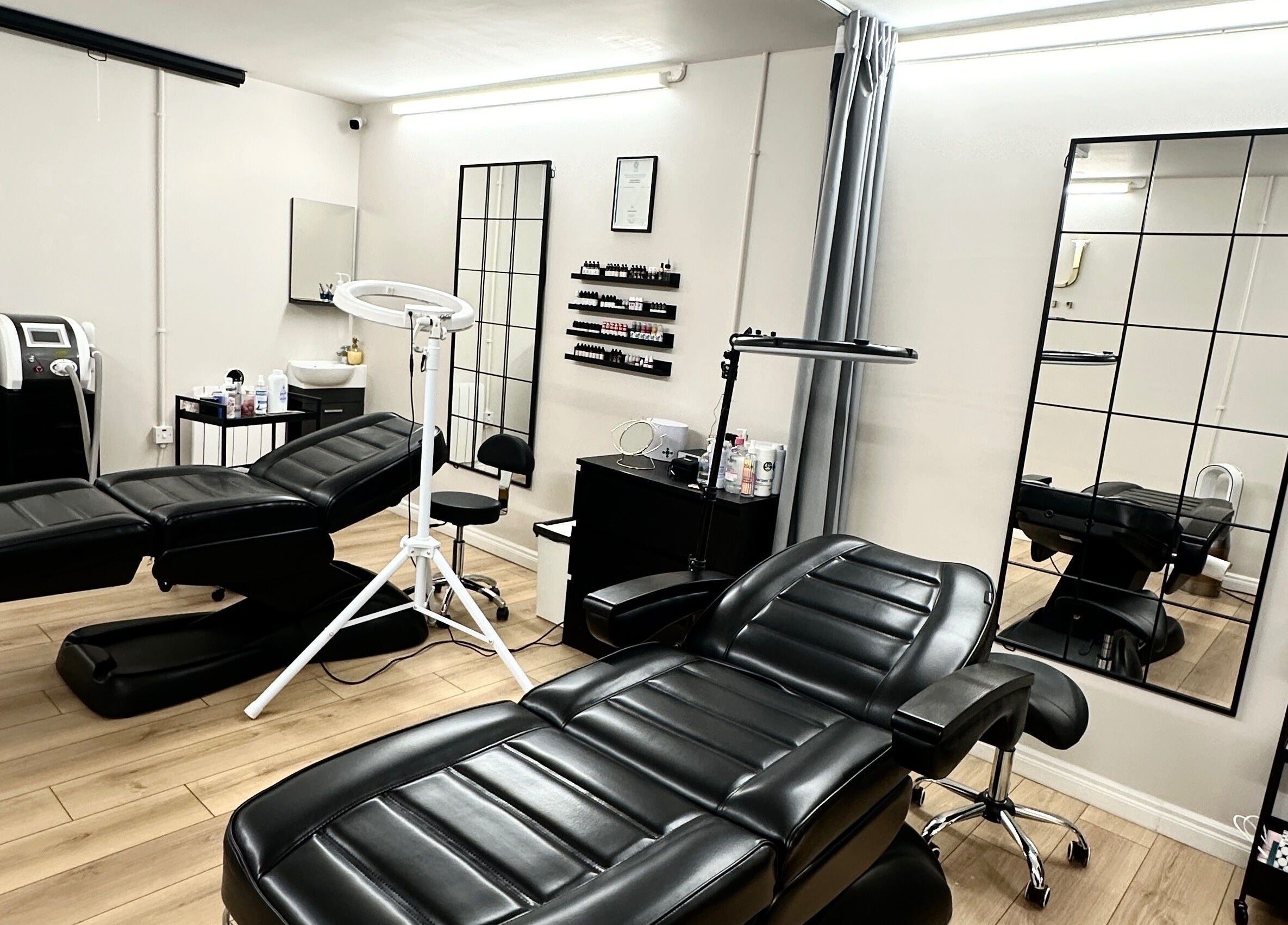 Modern treatment room at Unique Permanent Makeup, Tralee, County Kerry, IE, featuring sleek black chairs and mirrors.