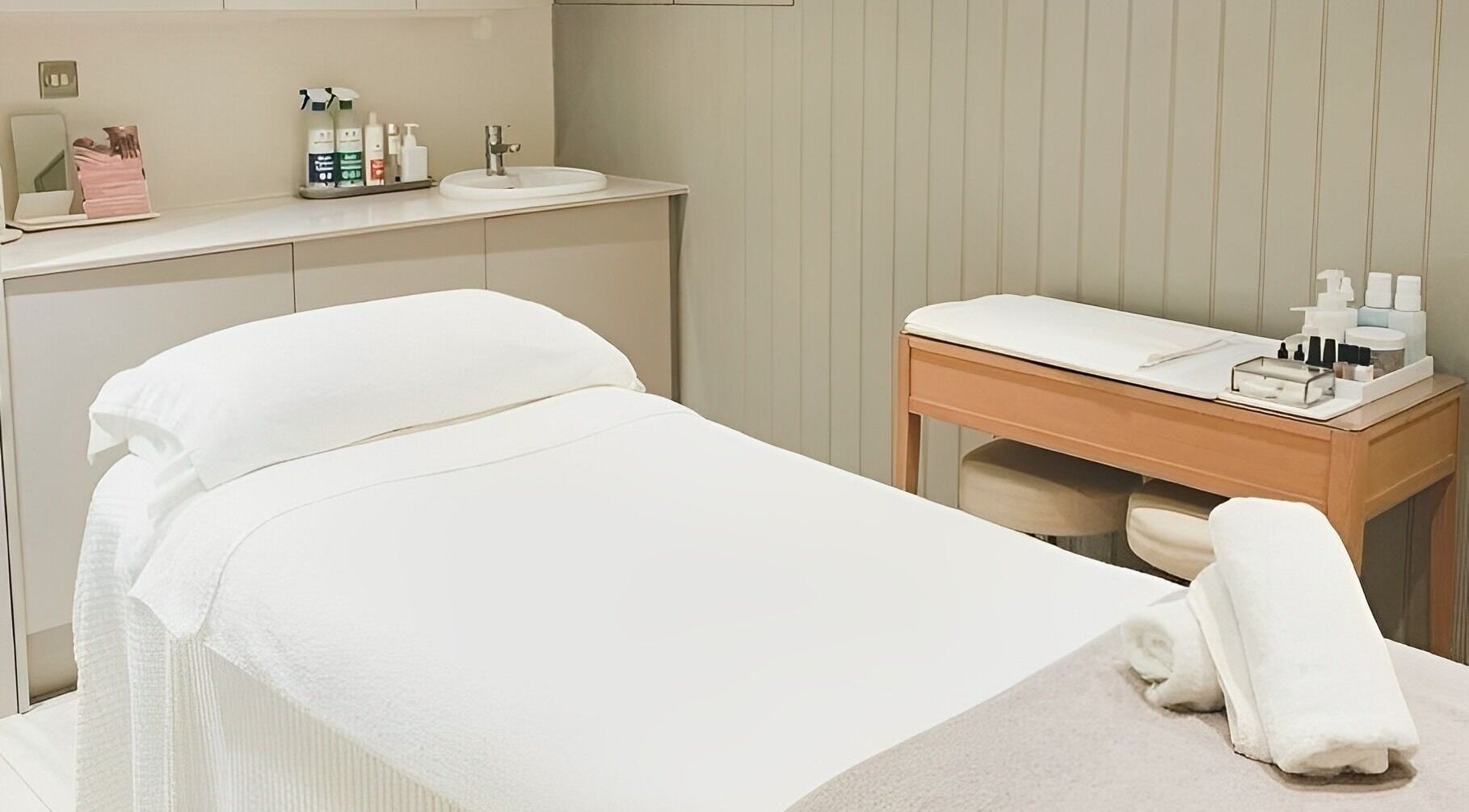 Treatment room at Moreton Place Beauty and Wellbeing in London, England, GB. Crisp white bed and cozy decor.