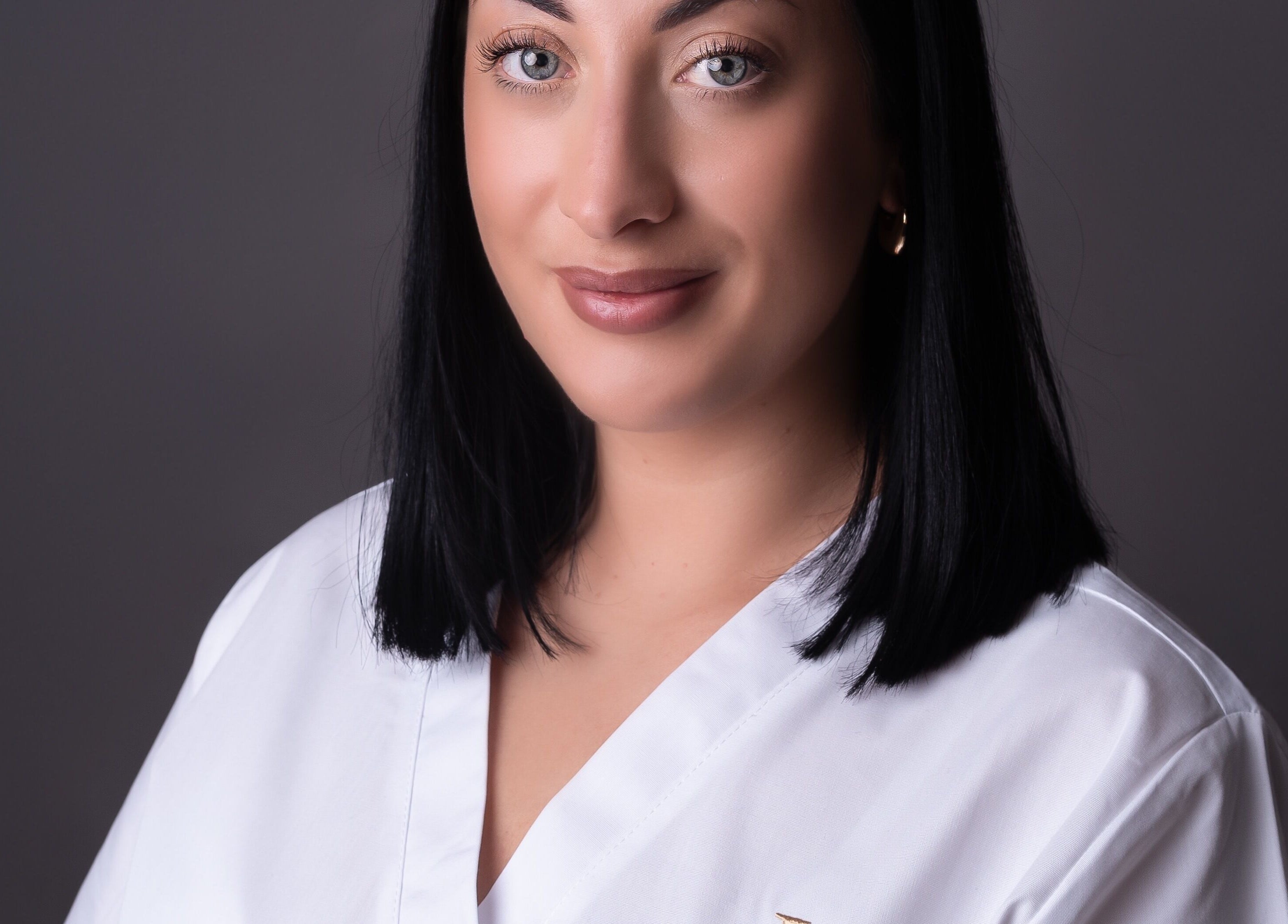Professional beautician at Adara Ink, Chadderton, England, GB in a clean white uniform.