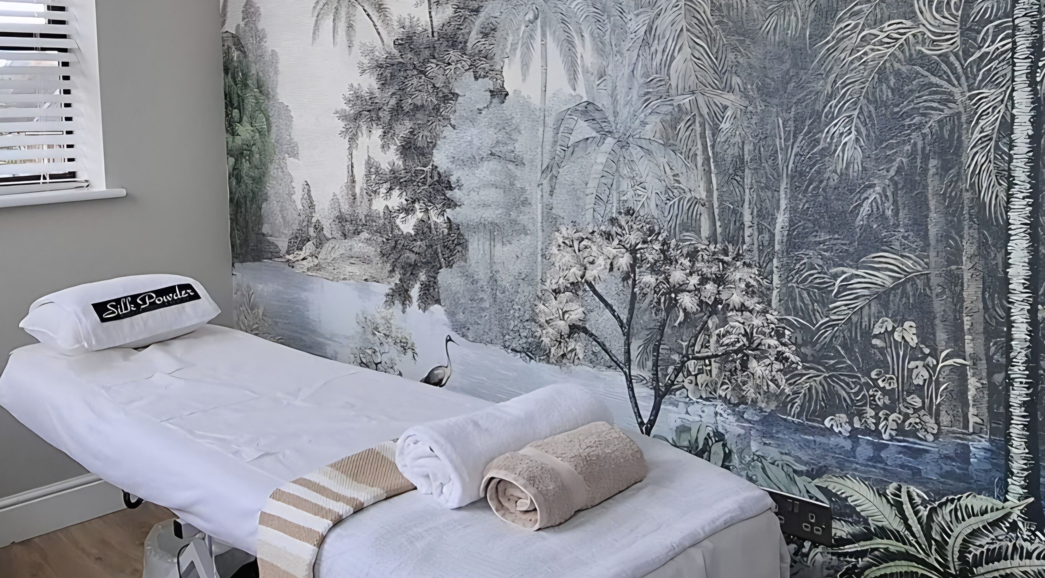 Tranquil spa room at Silk Powder Limited, Leicestershire, GB, featuring massage table and soothing mural.