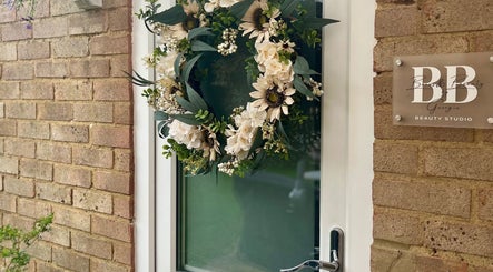 Elegant floral wreath decorates the door of Brows & Beauty by Georgia in Effingham, England, GB.