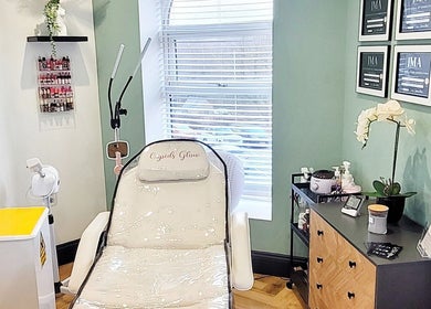 Elegant treatment room at Cupids Glow, Bolton, England, GB with a plush chair, certificates, and skincare products.