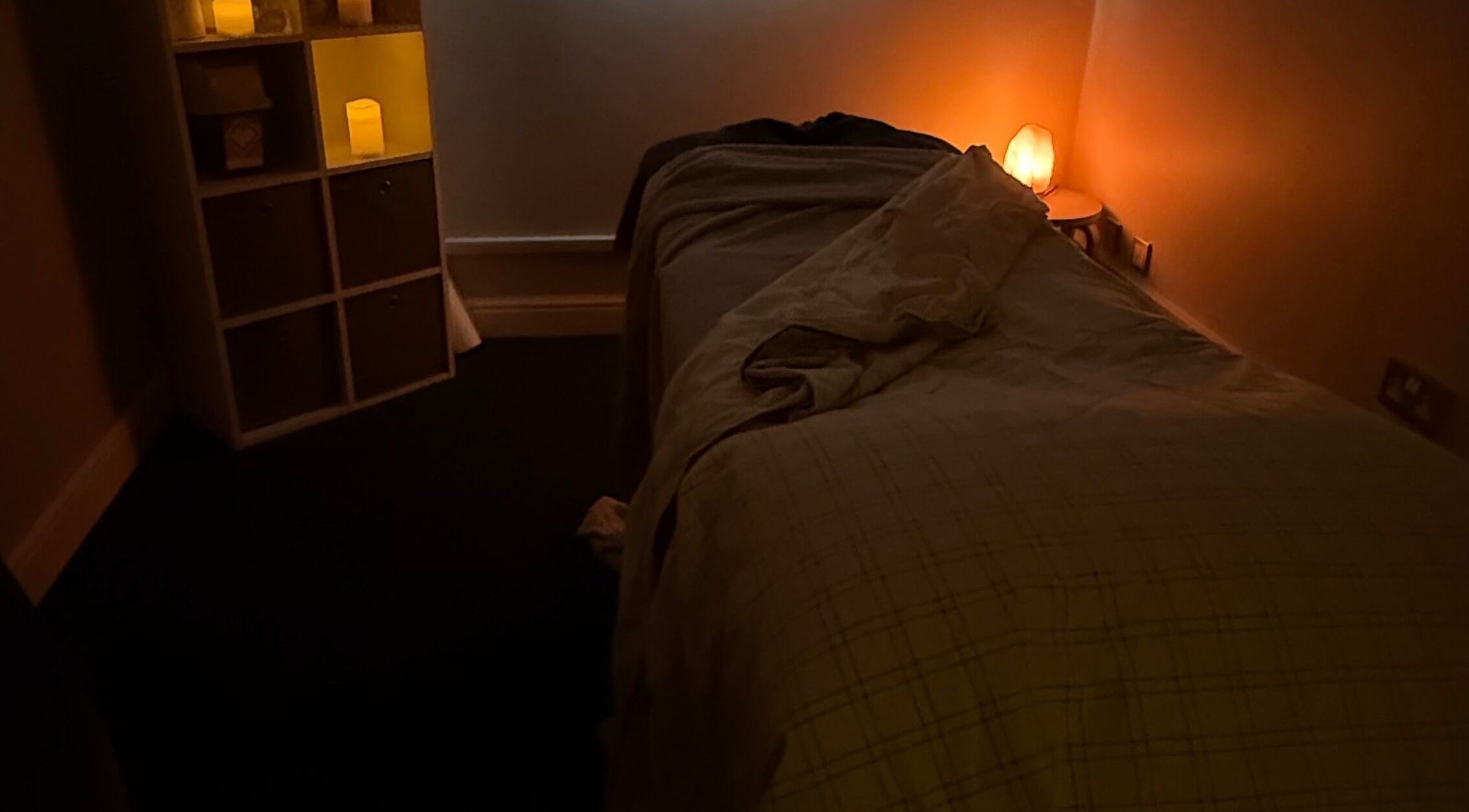 Tranquil massage room at MASSAGE BY ZOE in Corby, England, GB with warm lighting and a comfortable bed.