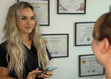 A SKNFORM professional welcomes a client at Newton-le-Willows, England, GB with certificates in the background.