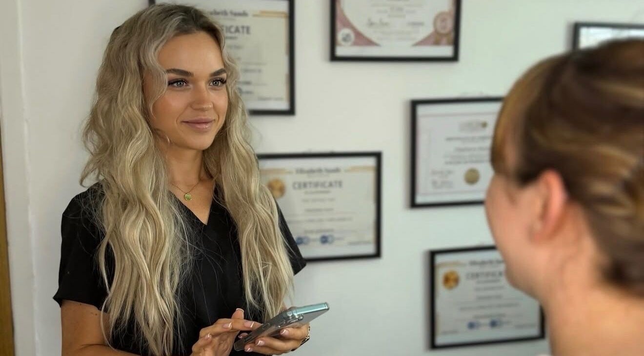 A SKNFORM professional welcomes a client at Newton-le-Willows, England, GB with certificates in the background.