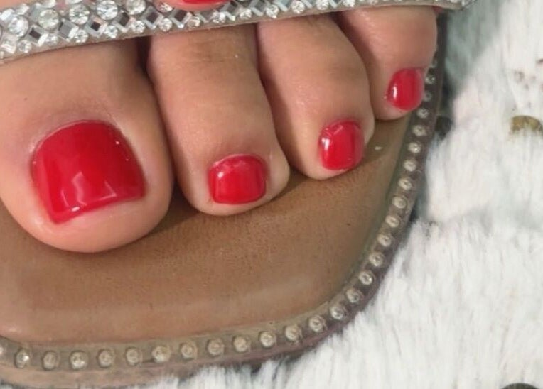 Vibrant red pedicure at House of pedi’s by Lydia in Tucson, Arizona, US enhances beauty in jeweled sandals.