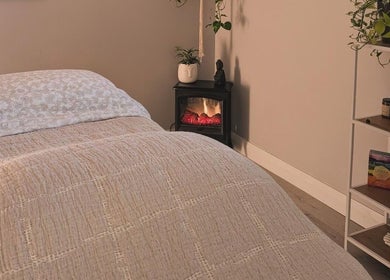 Peaceful massage room at The Celestial Root, Belleville, Ontario, CA, featuring a bed and calming decor.