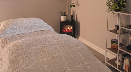 Peaceful massage room at The Celestial Root, Belleville, Ontario, CA, featuring a bed and calming decor.