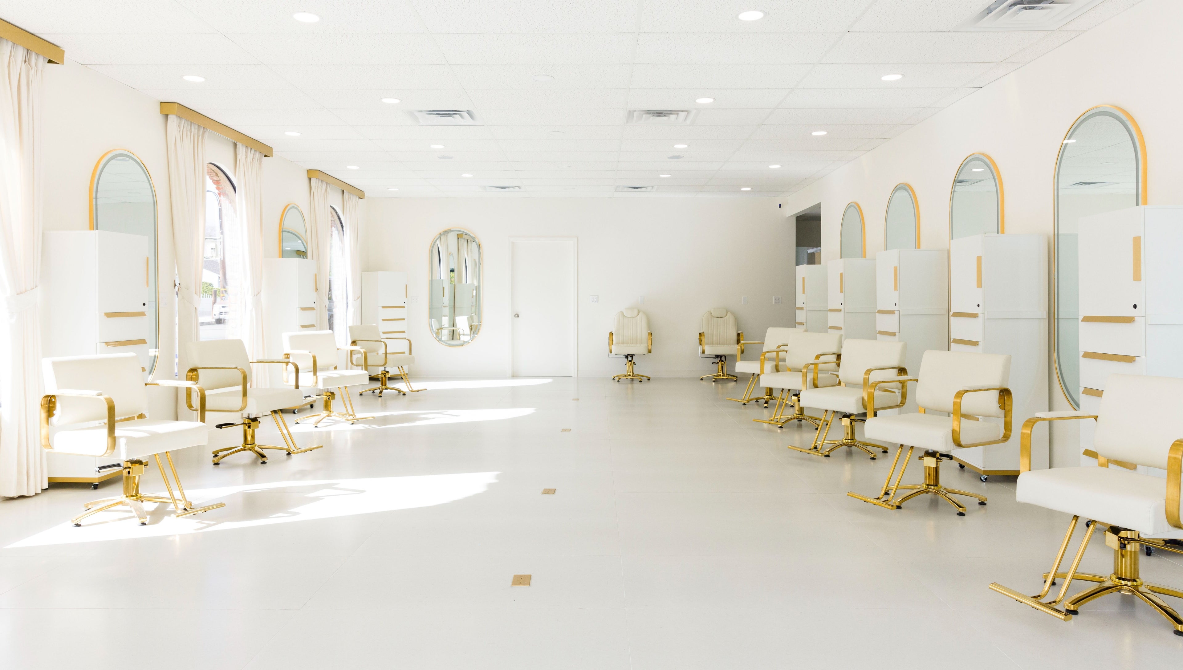 Bright, elegant interior of Stardust Hair Salon in Burbank, California, US with white and gold chairs.