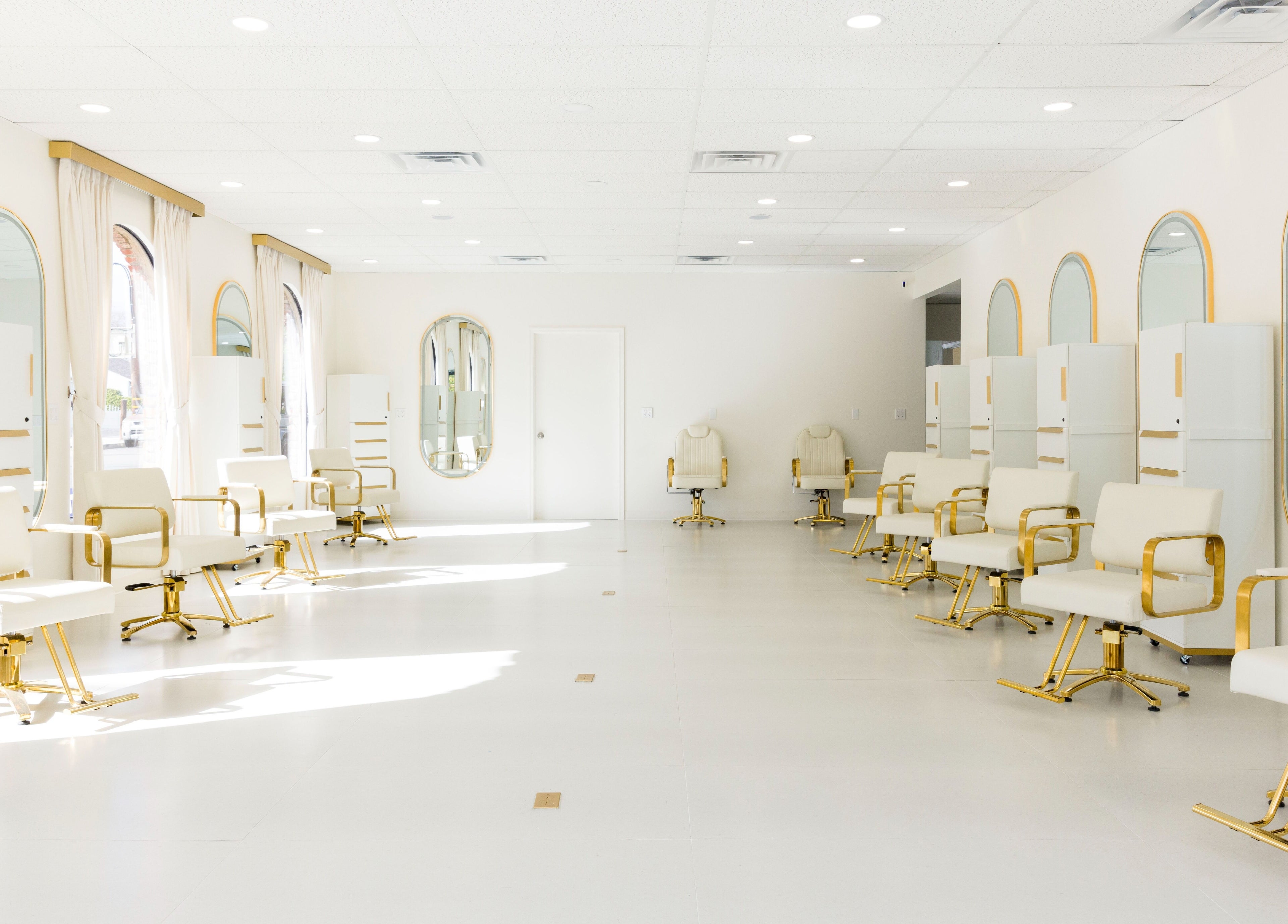 Bright, elegant interior of Stardust Hair Salon in Burbank, California, US with white and gold chairs.