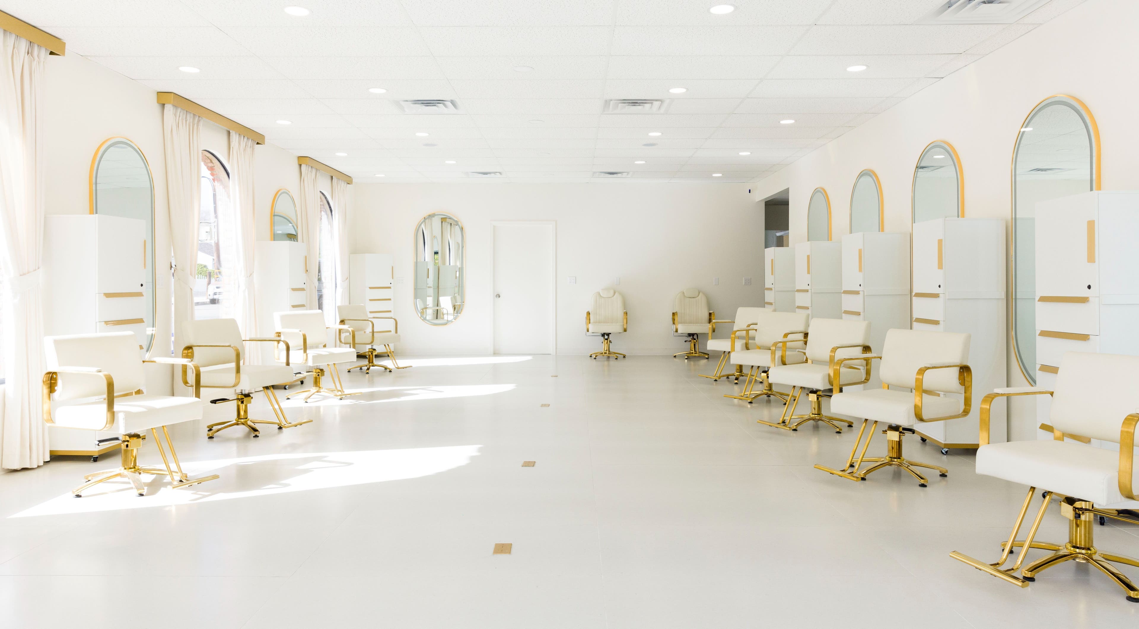 Bright, elegant interior of Stardust Hair Salon in Burbank, California, US with white and gold chairs.