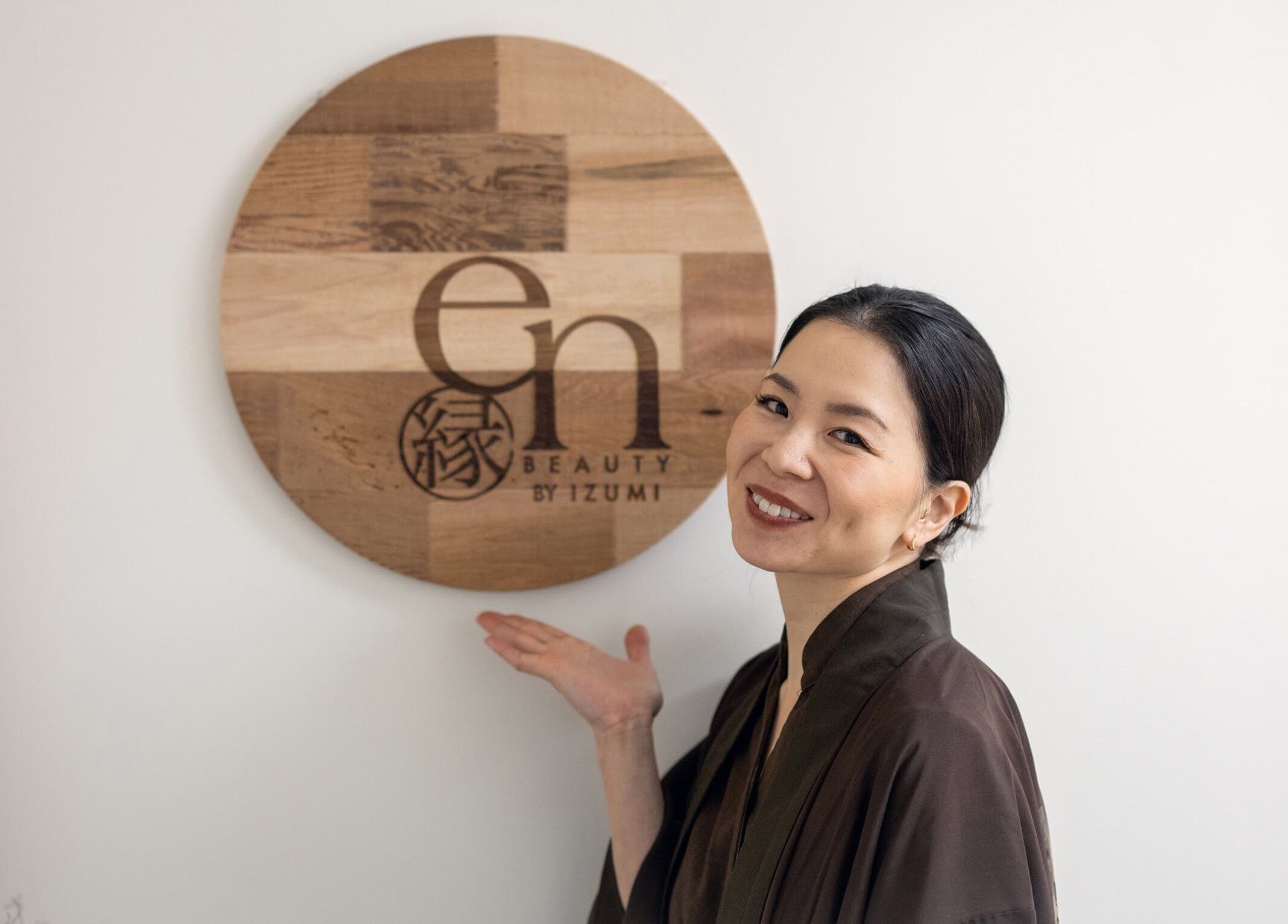 Smiling individual presenting En Beauty lash and Japanese Face Lift sign in Auckland, Auckland, NZ.