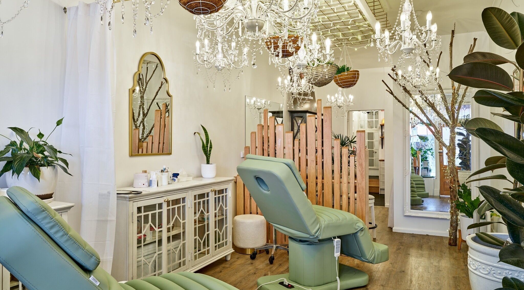 Chic interior of Boutique Brows Body & Skin in Hobart, Tasmania, AU with plush green chairs and crystal chandeliers.