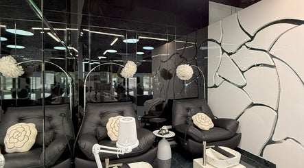 Relaxing lounge at L'Art de Coiffure Salon, Dubai, Dubai, AE with stylish black chairs and elegant decor.