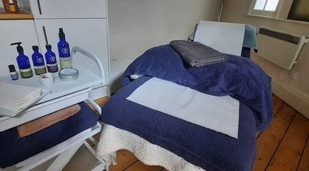 Cozy treatment bed at Essential Bodywork by Sara Colautti, Swansea, Wales, GB, with skincare products.