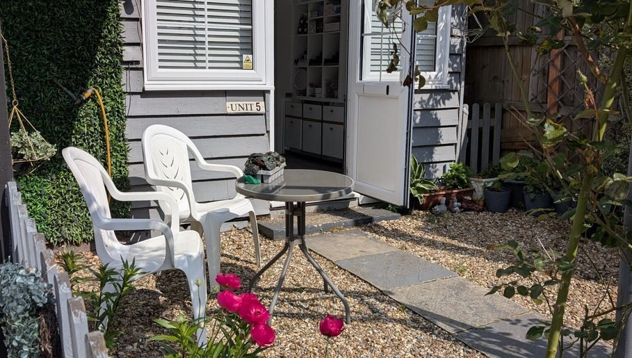 Charming outdoor entrance at Tetyana's Beauty, Colchester, England. Cozy chairs and table on a pebbled path.