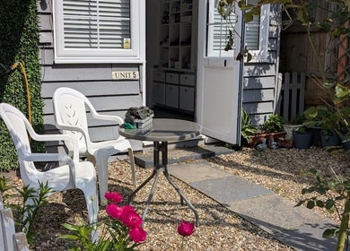 Charming outdoor entrance at Tetyana's Beauty, Colchester, England. Cozy chairs and table on a pebbled path.