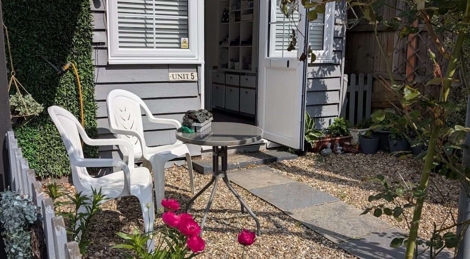 Charming outdoor entrance at Tetyana's Beauty, Colchester, England. Cozy chairs and table on a pebbled path.