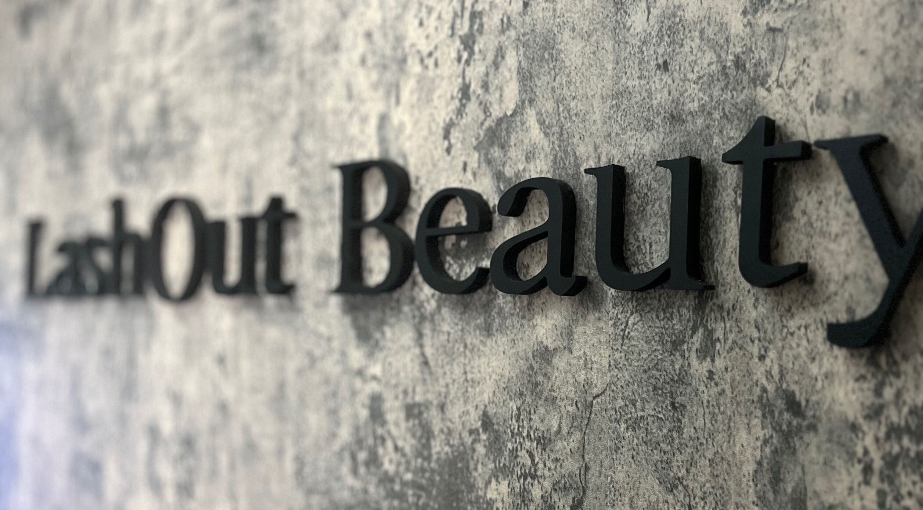 Close-up of Lash Out Beaut sign on textured wall in Houston, Texas, US.