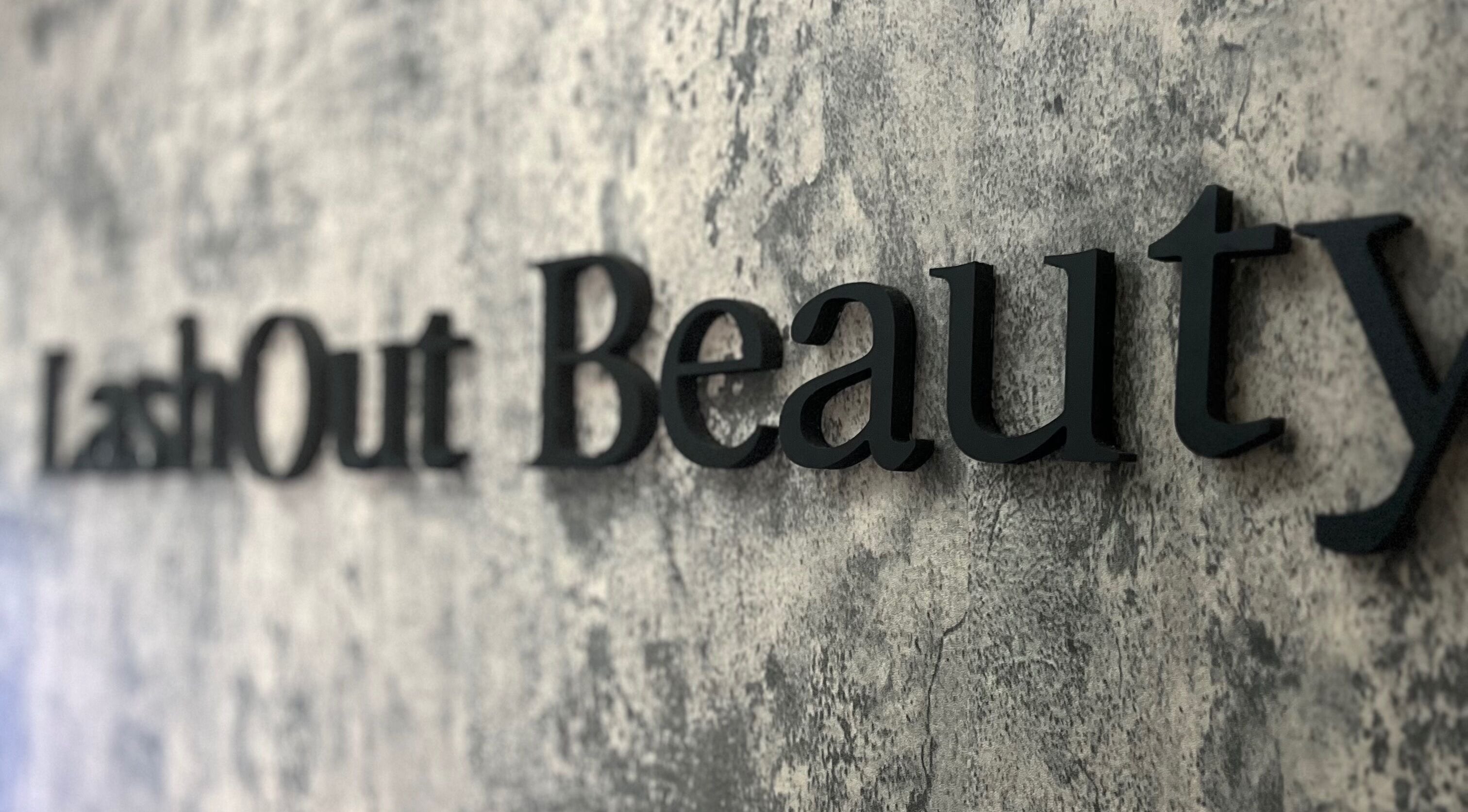 Close-up of Lash Out Beaut sign on textured wall in Houston, Texas, US.