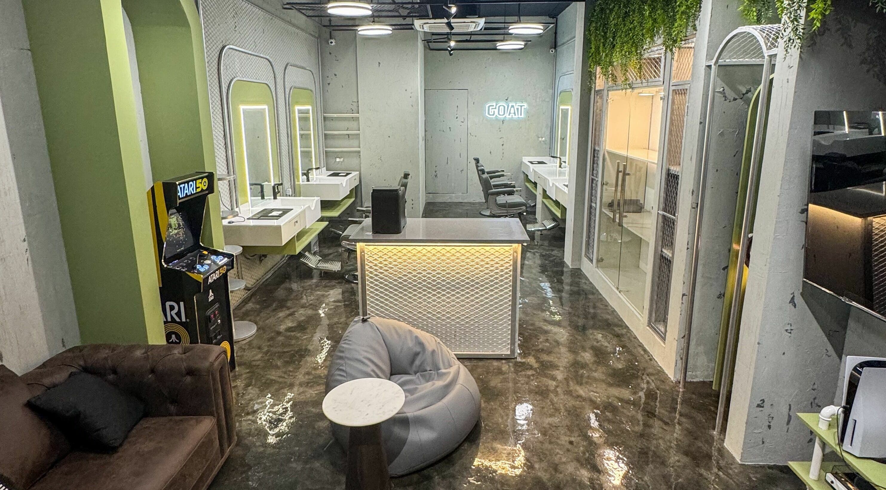 Stylish interior of GOAT Barber in Muscat, OM, featuring modern décor and arcade game.
