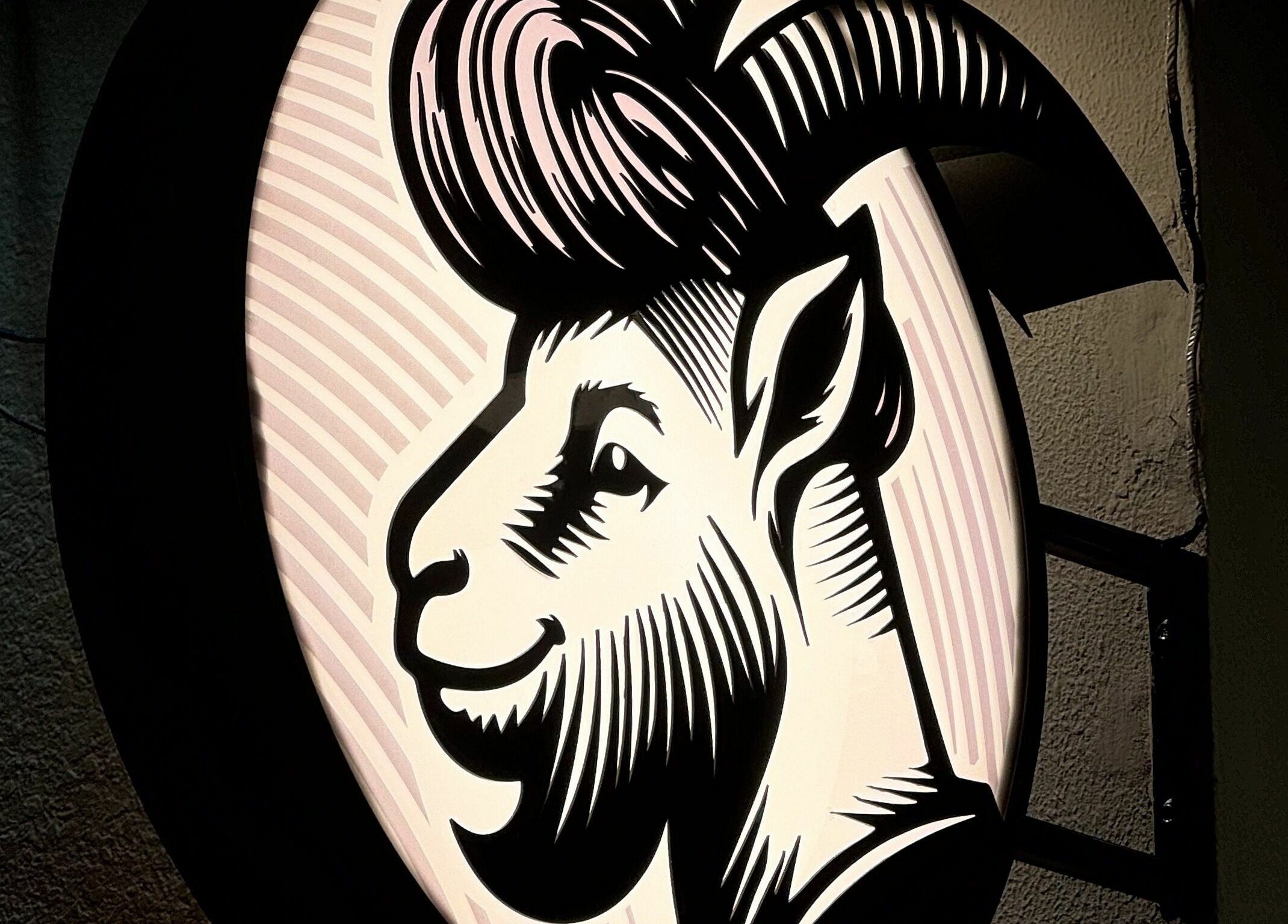 Illuminated goat logo sign of GOAT Barber in Muscat, Muscat Governorate, OM, showcasing unique branding.