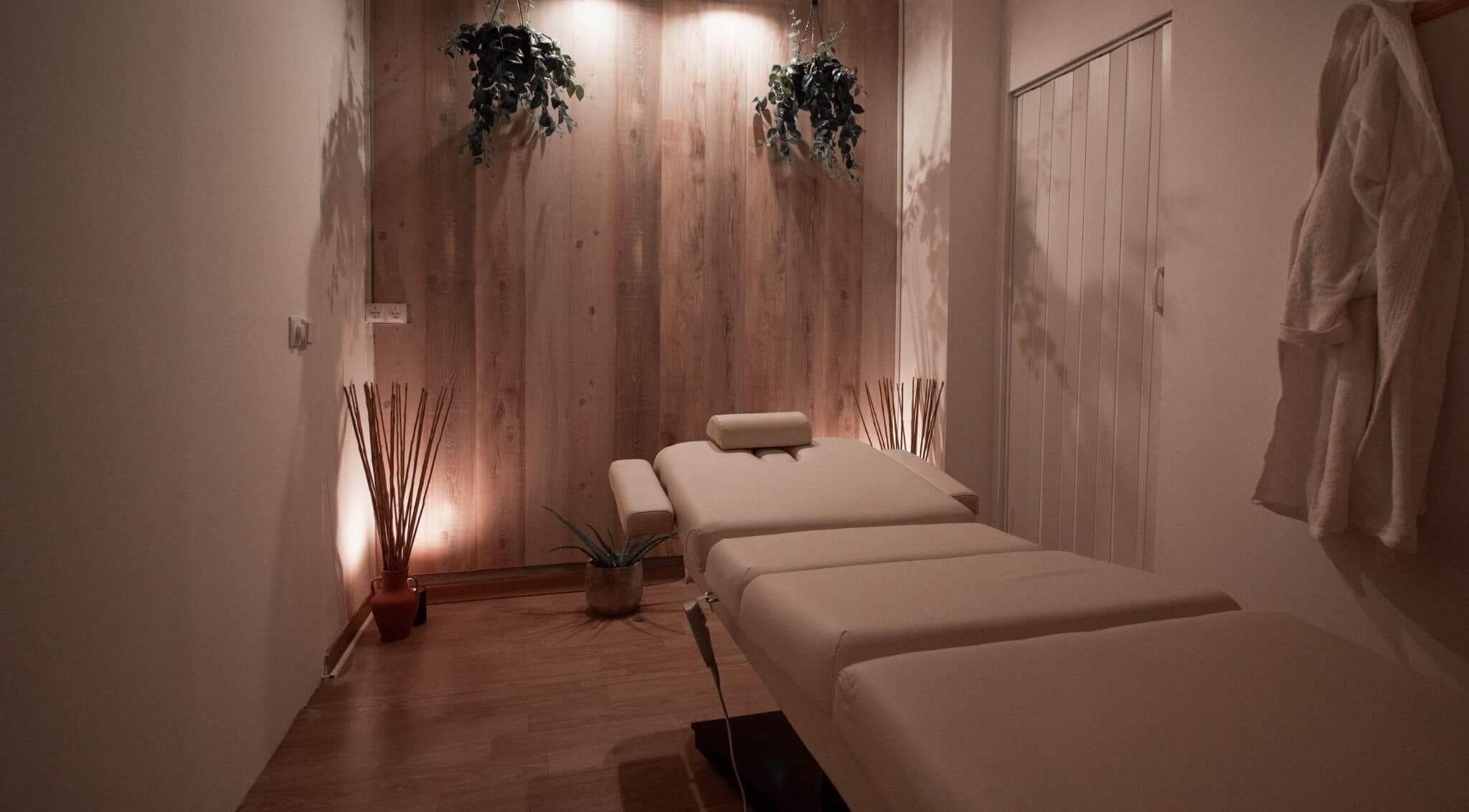 Sala de tratamiento en Mímate Estética Avanzada, Torredembarra, Catalunya, ES con cama de masaje y decoración serena.