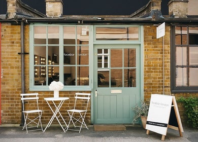 Facebar London's charming entrance with teal doors and white chairs, located in London, England, GB.