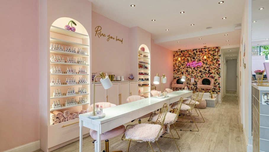 Interior of WINK Beauty in London, England, GB, elegant pink decor with nail polish display and floral wall.