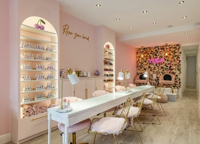 Interior of WINK Beauty in London, England, GB, elegant pink decor with nail polish display and floral wall.