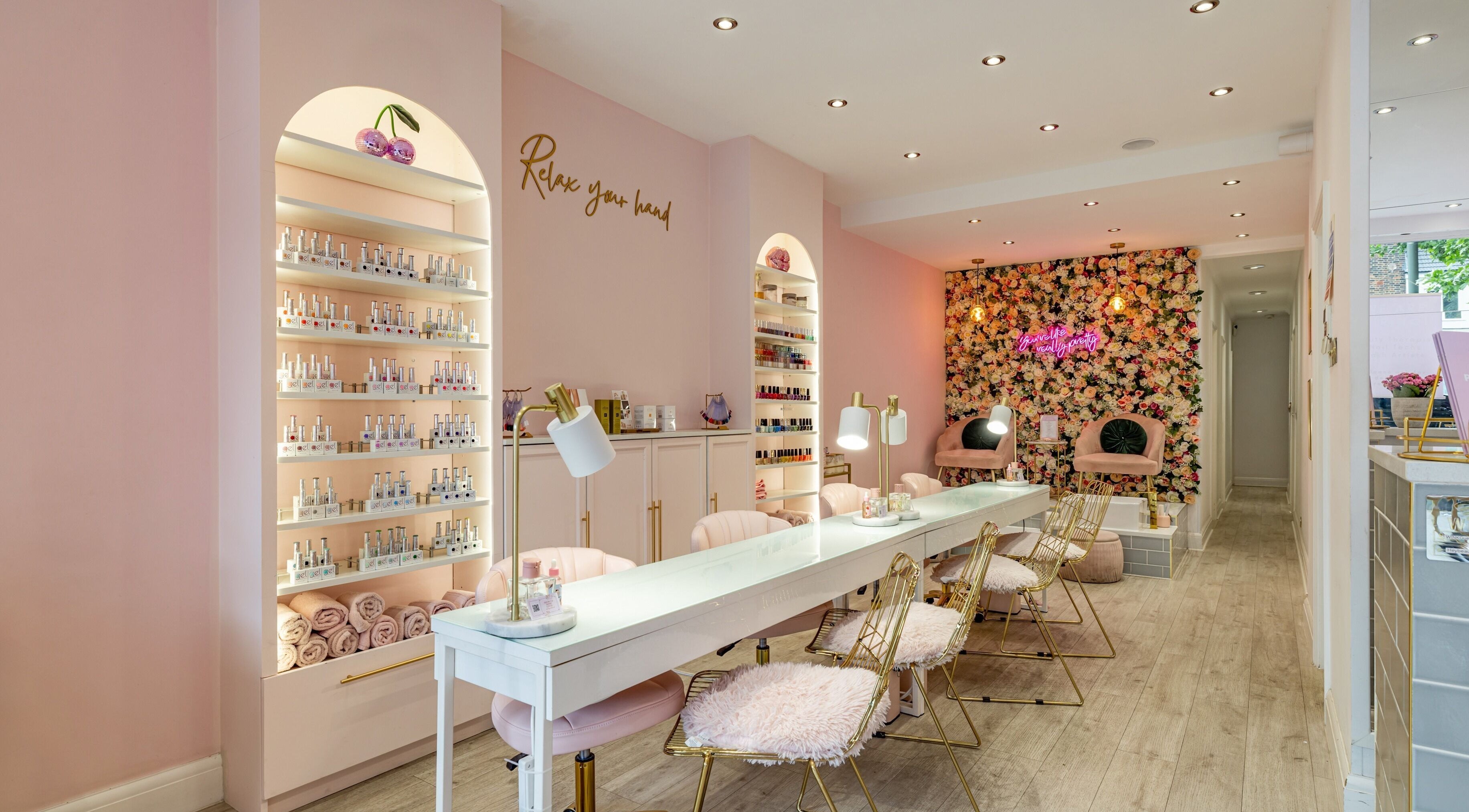 Chic, flower-adorned interior at WINK Beauty - Whetstone, London, England, GB, showcasing nail stations.