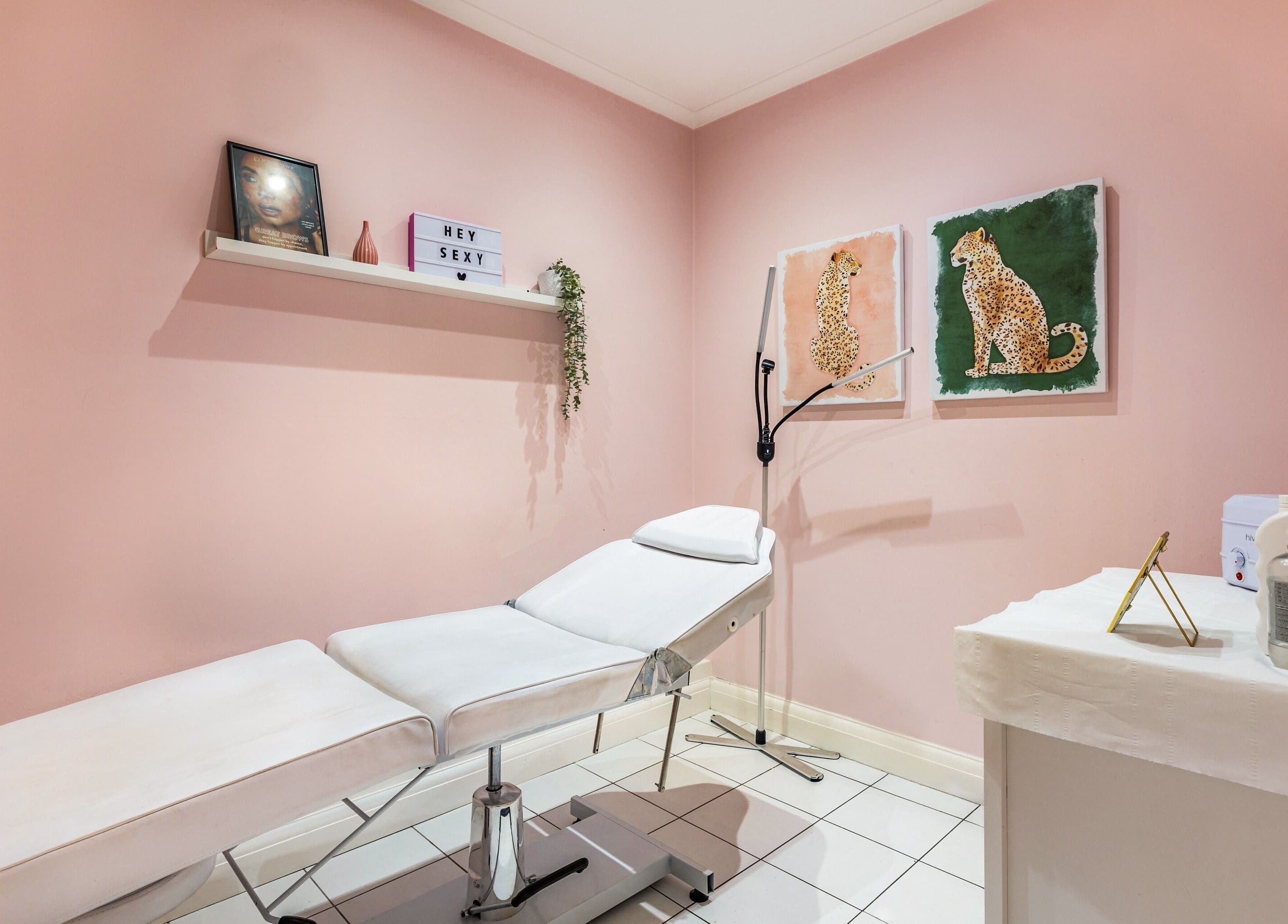 Cozy therapy room at WINK Beauty - Whetstone, London with pink walls and treatment bed.