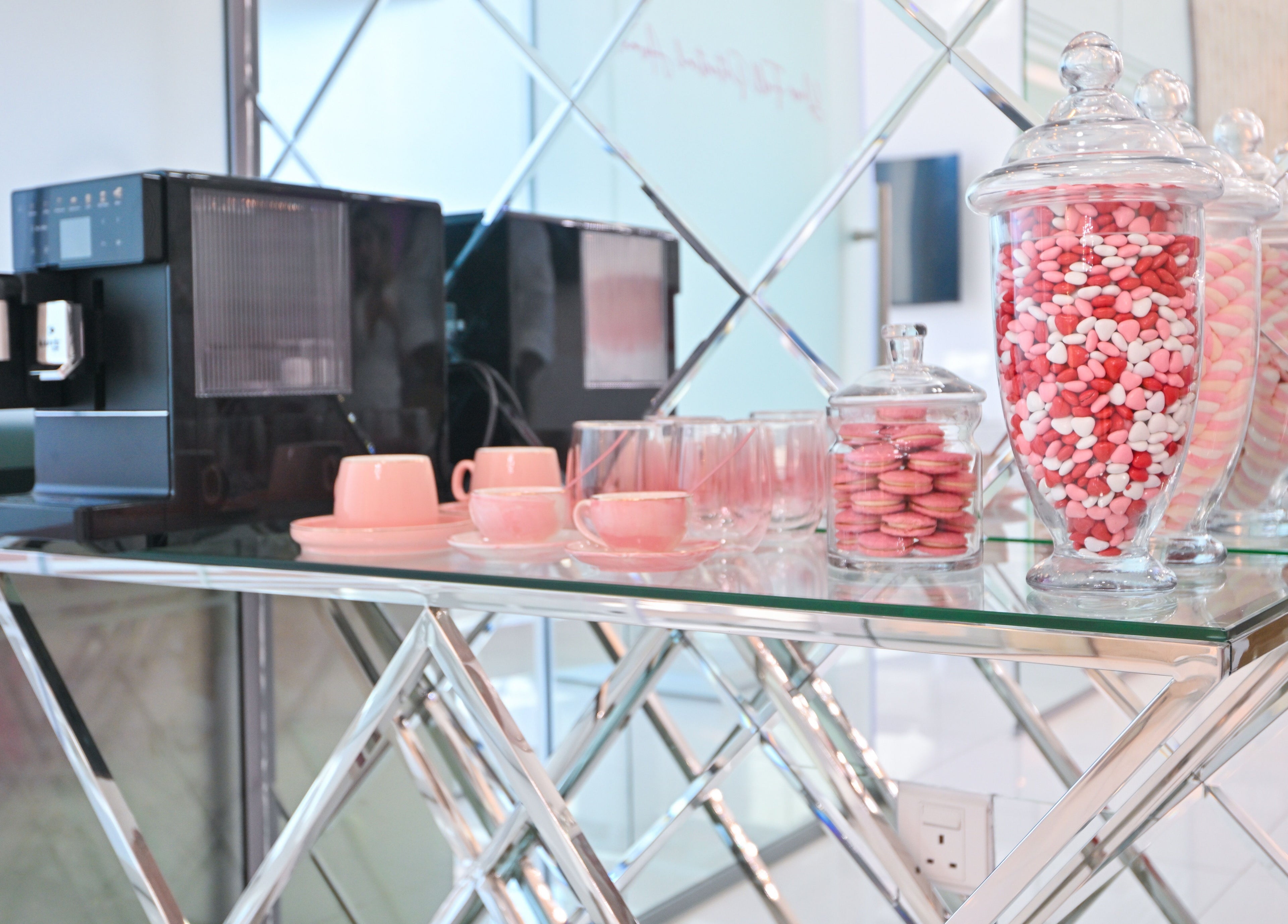 Chic refreshment area at Snatch & Glow London in Dubai, featuring coffee machine, pink cups, and sweets jars.