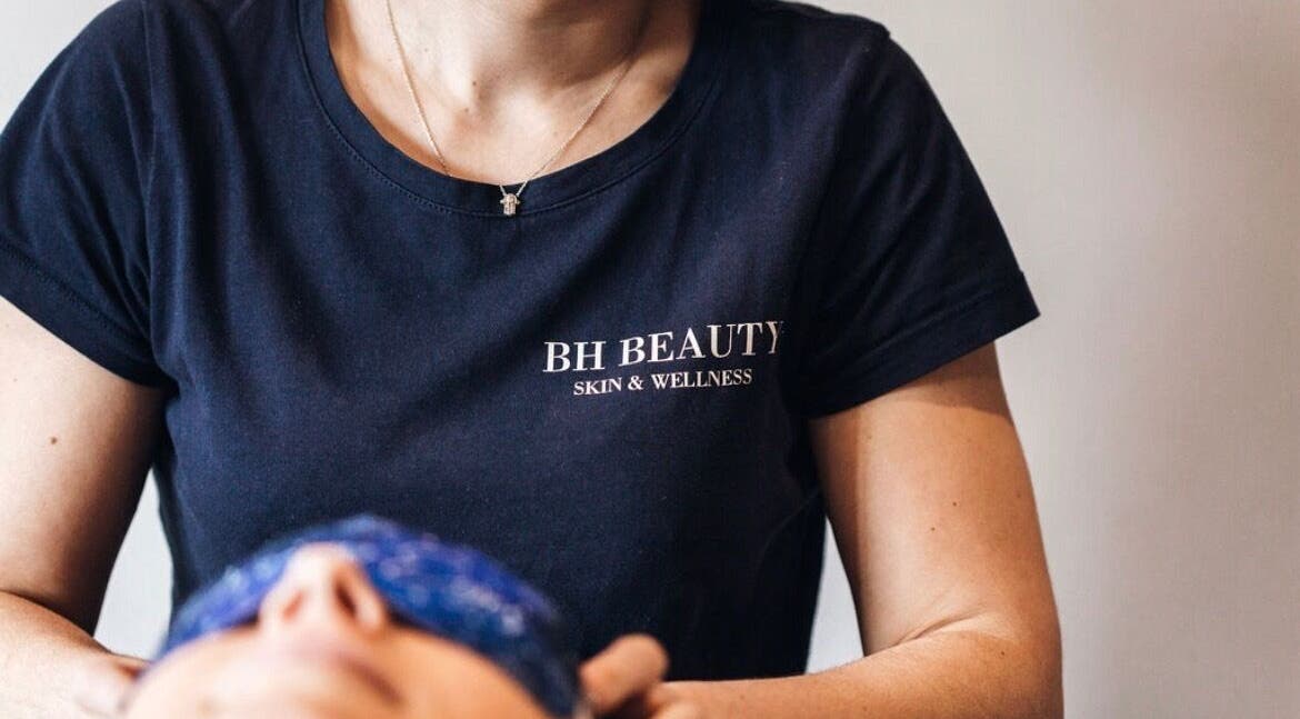 Therapist in BH Beauty Room shirt performing facial in Poole, England, GB.