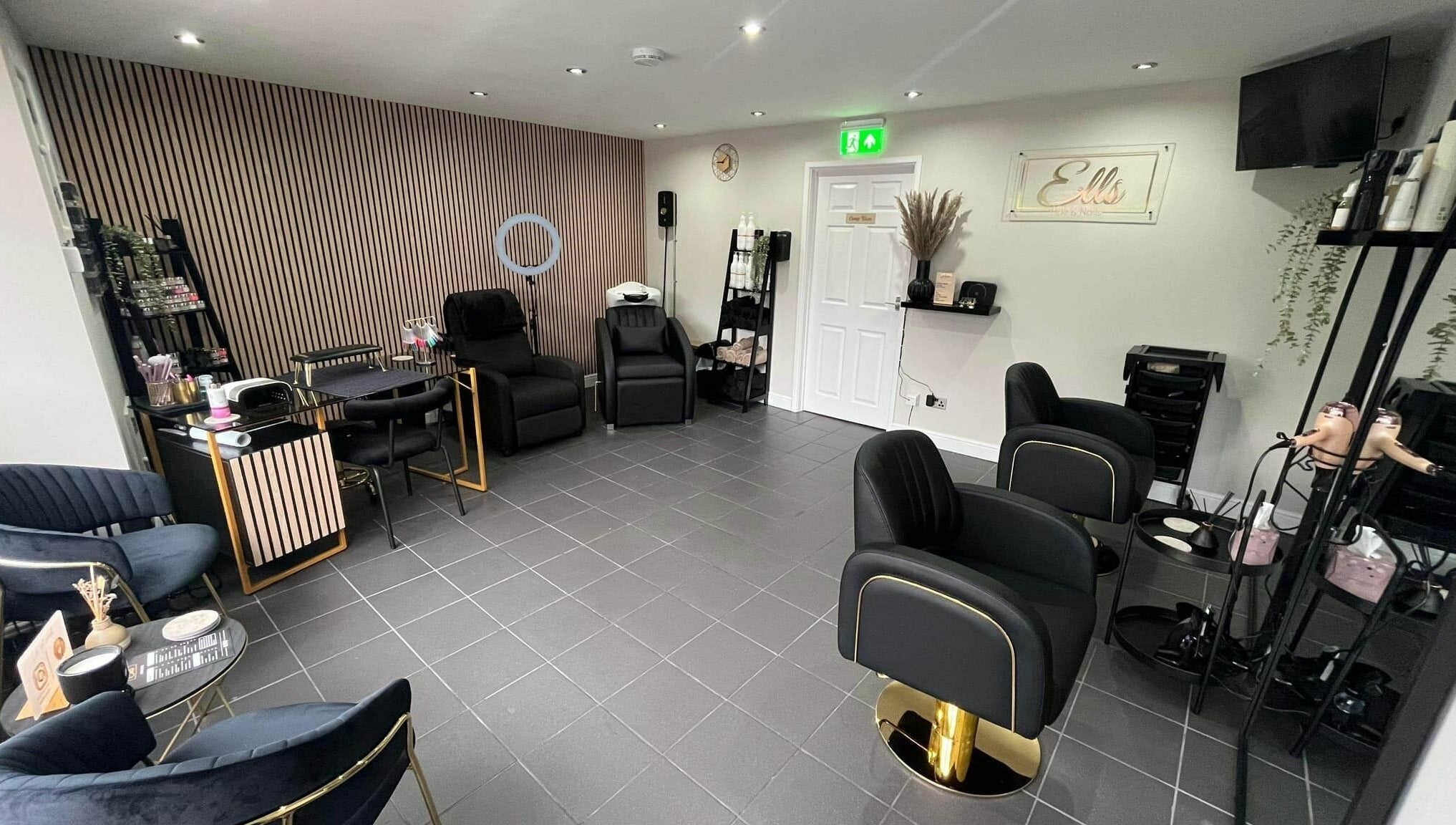 Modern, stylish interior of Ells Hair and Nails, Callington, England, GB, featuring comfortable black chairs.