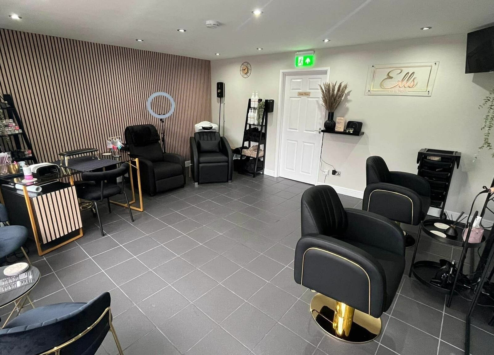 Modern, stylish interior of Ells Hair and Nails, Callington, England, GB, featuring comfortable black chairs.