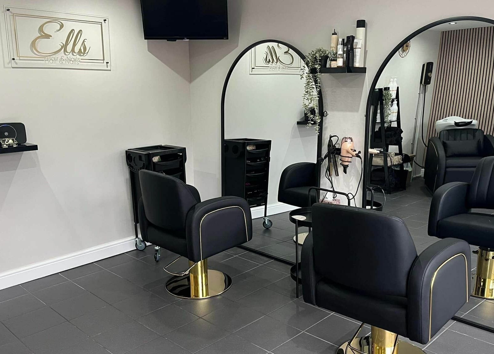 Modern salon interior at Ells Hair and Nails in Callington, England, GB, featuring sleek black chairs and mirrors.